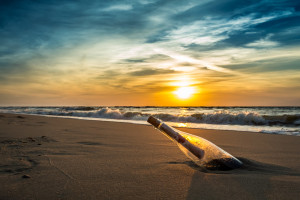 Message in a bottle on a beach against the setting sun